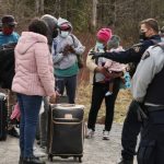Asylum seekers talk to a police officer as they cross into Canada from the US, near a checkpoint on Roxham Road near Hemmingford, Quebec, April 24, 2022